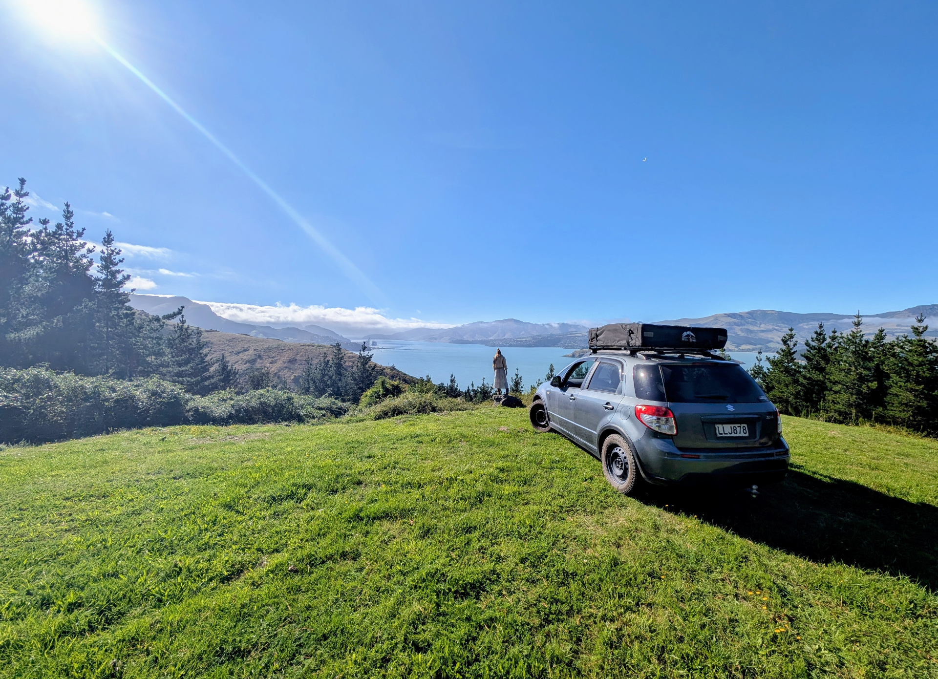 Campervan parked on a grassy hilltop overlooking Lyttelton Harbour, Whakaraupō